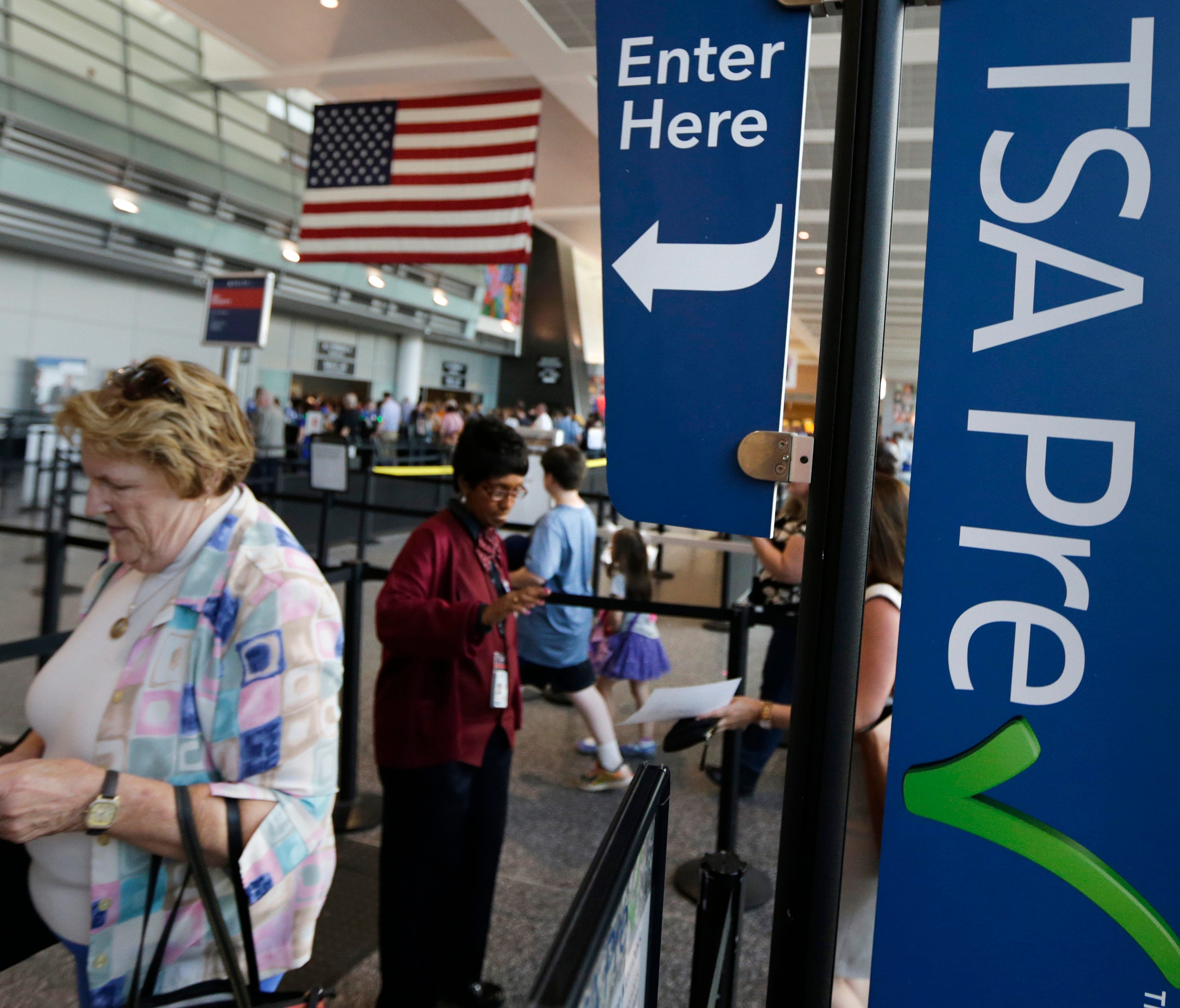 Travelers pass a sign for the Transportation Security Administration's Precheck line as they walk to their departure gate in Terminal A at Logan International Airport on June 27, 2016, in Boston.