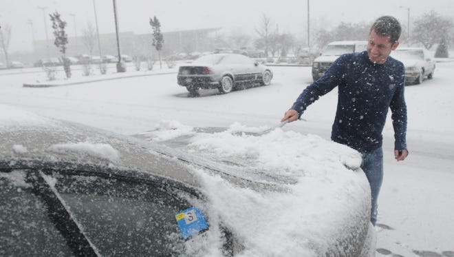 UW-Oshkosh student Josh Lyons finds his car covered in snow Nov. 24. He was prepared with a brush to clear his car of the snow.