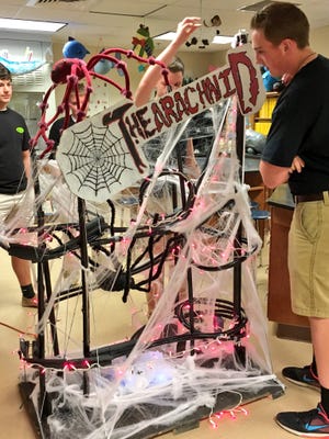 Buckeye High Advanced Placement physics student Caleb Rhodes (back) places a marble atop "The Arachnid," his group's marble roller coaster project, as senior Jonathan Crawford (right) and other group members watch.