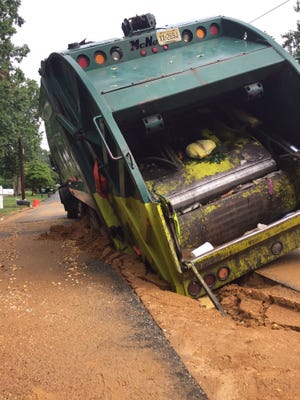 A trash truck gets stuck in a trench on Peach Drive in Millville Friday morning.