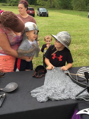 Josh Keith, 6, shows off a helmet and chain mail to his brother, Sullivan, 2, and Wendy Barrett. They're from Lexington.