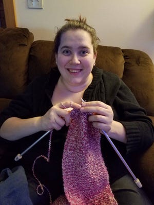 Sarah Kreager knits a scarf that she hopes will warm the neck of someone in need.
