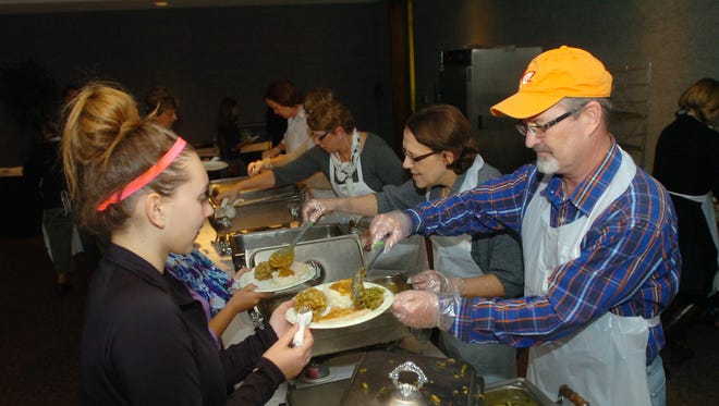 
Mike Durhan serves a helping of green beans to Natalia Peurach green at the 3rd Annual Community Thanksgiving Feast at the Costick Center.
