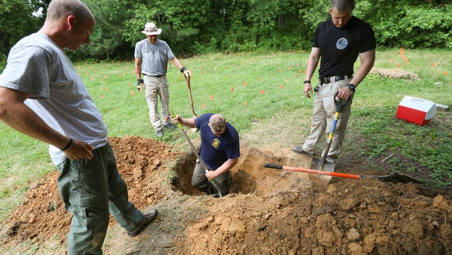 From left, Cpl. Jeff Miller, Cpl. Lenny Aguilar and Trooper Benjamin Nefosky take a break one hot summer afternoon while Cpl. James Agnor digs for the remains of Delaware State Police dog Captain, who is buried in the Delaware SPCA pet cemetery in Stanton.