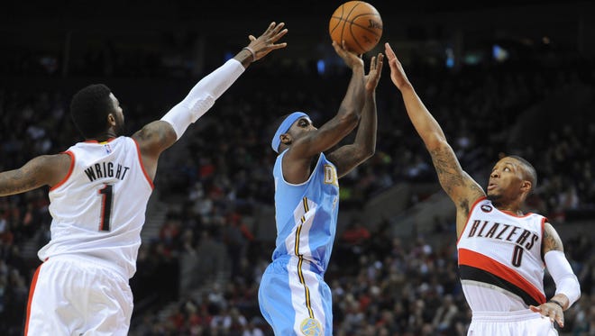 Denver Nuggets' Ty Lawson, center, shoots against Portland Trail Blazers' Dorell Wright (1) and Damian Lillard (0) during the first half of an NBA basketball game in Portland, Ore., Saturday, March 28, 2015.