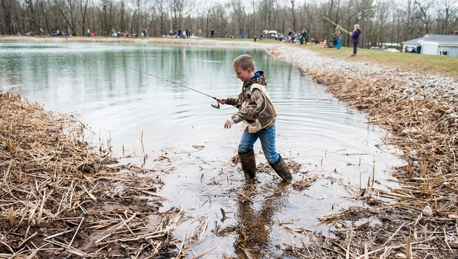Drake Boyer, 8, trudges throught mud and water to get to a prime fishing spot at Kaiser Lake in New Oxford on Saturday. The McSherrystown Fish and Game Association sponsored a free, all-day, youth event to mark the first day of trout season. 