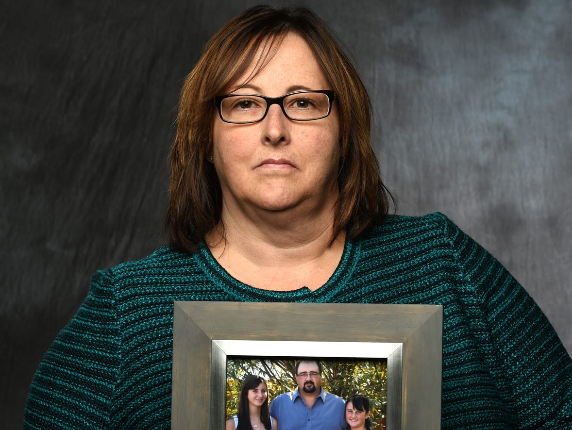 Kathy Monaco poses for a portrait on Oct. 22, 2015, holding a picture of her husband Russ and daughters Mallory, left, and Madison. Russell Monaco died in 2011 at the age of 47.