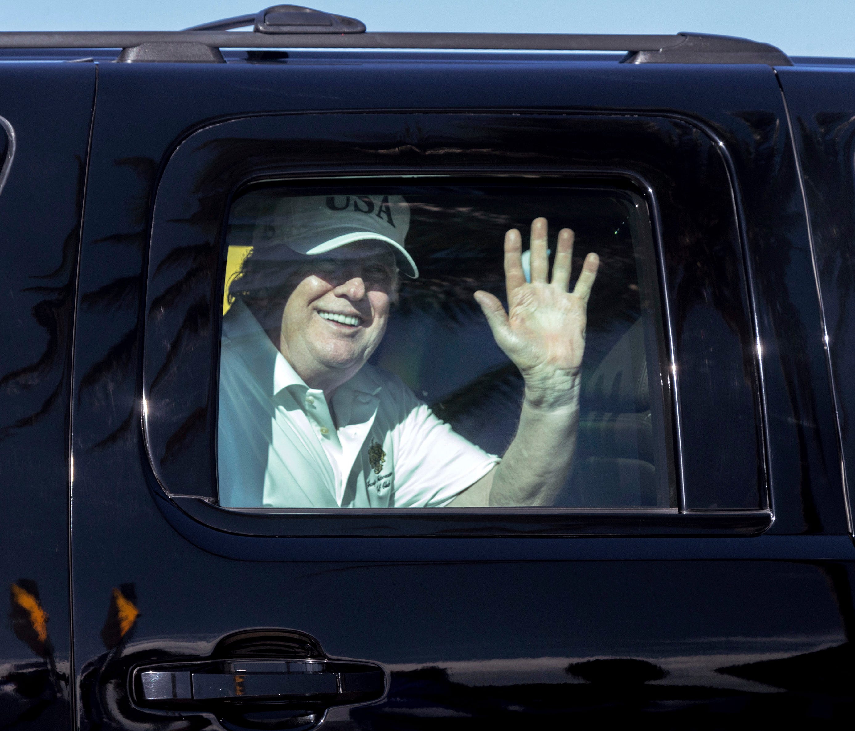 President Trump waves to supporters from his motorcade traveling along Southern Blvd. enroute to his Mar-a-Lago estate from Trump International Golf Club, Dec. 28, 2017, in West Palm Beach, Fla.