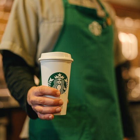 Starbucks barista holding a cup of coffee.