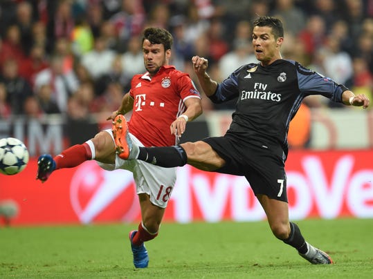 Munich's  Juan Bernat, left, and Real Madrid's Cristiano Ronaldo, right, challenge for the ball during the Champions League quarterfinal first leg soccer match between FC Bayern Munich and Real Madrid, in Munich, Germany, Wednesday, April 12, 2017. (Andreas Gebert/dpa via AP)