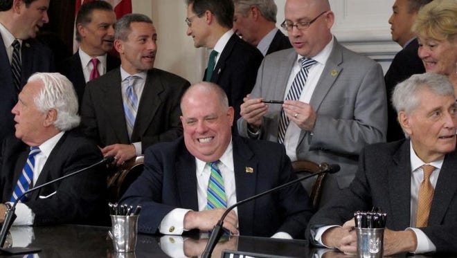 Maryland Gov. Larry Hogan, center, smiles after signing a bill to ban the hydraulic drilling practice known as fracking in the state on Tuesday, April 4, 2017 in Annapolis, Md. The Republican governor had just passed a pen to Del. David Fraser-Hidalgo, a Democrat who sponsored the legislation and is standing behind Hogan. Maryland is the first state where a legislature has voted to bar the practice that actually has natural gas reserves. (AP Photo/Brian Witte)