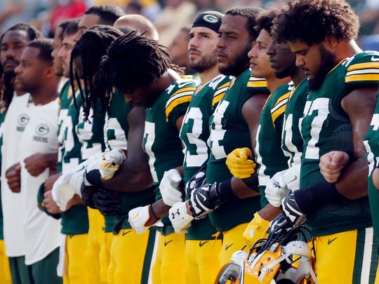 FILE - In this Sunday, Sept. 24, 2017, file photo, members of the Green Bay Packers lock arms during the national anthem before an NFL football game against the Cincinnati Bengals in Green Bay, Wis. The Packers plan to lock arms during the national anthem before Thursday night's game against the Chicago Bears, and they are asking fans to do the same in what they say will be a "moment of unification.” (AP Photo/Mike Roemer, File