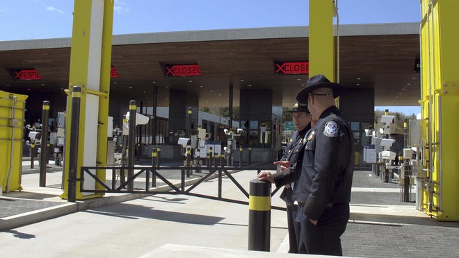 In this May 8, 2019 photo, U.S. Customs and Border Protection officials stand at the new border crossing facility on the U.S.-Canadian border in Derby Line, Vt. Some along the northern U.S. border are worried the temporary transfer of hundreds of border agents south could cause backups of people seeking to enter the United States from Canada during the busy summer tourist season. (AP Photo/Wilson Ring)