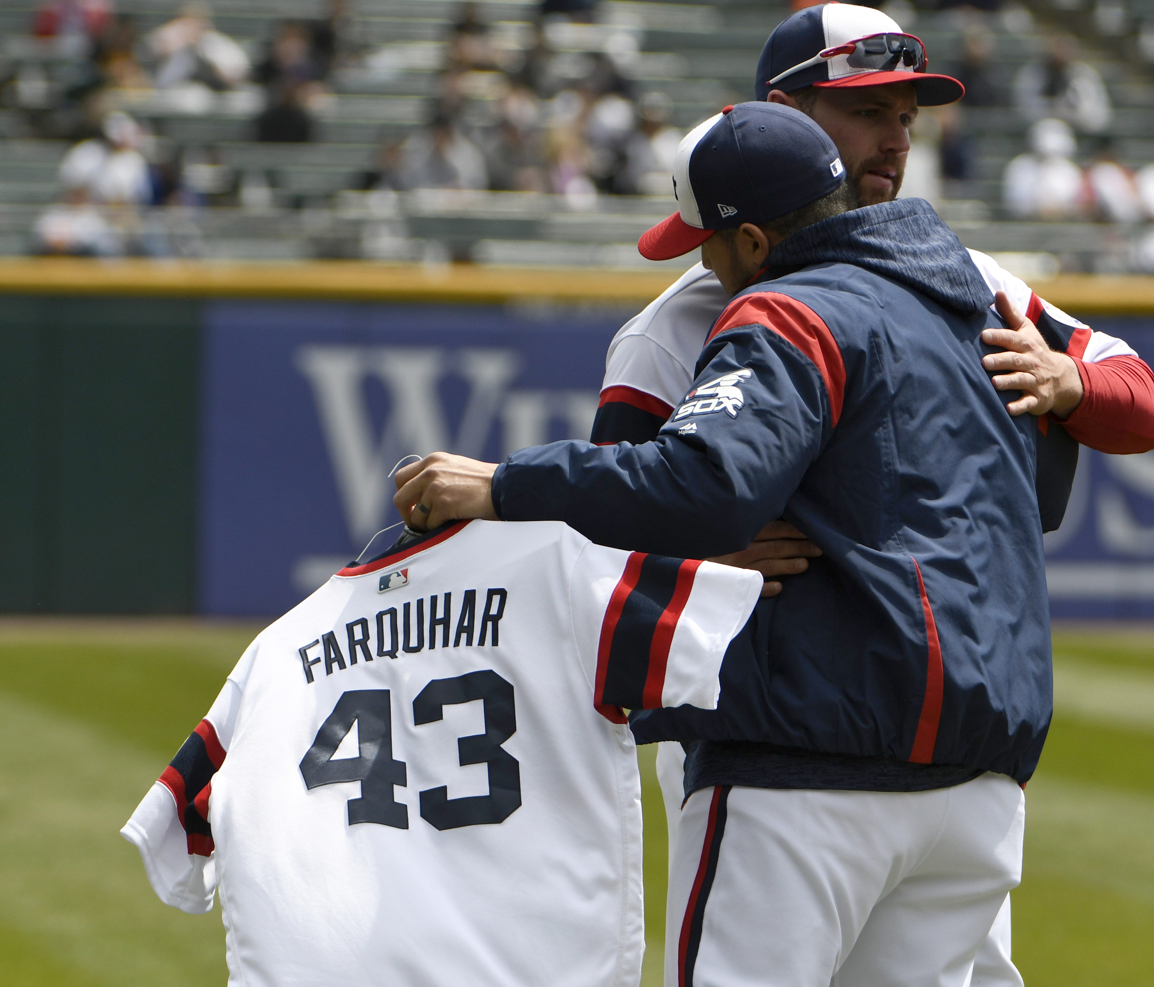 Hector Santiago, left, hugs Chris Volstad as he carries the jersey of Danny Farquhar to the bullpen before Sunday's game against the Astros.