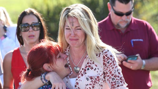 Parents wait for news after a report of a shooting at Marjory Stoneman Douglas High School in Parkland, Fla.