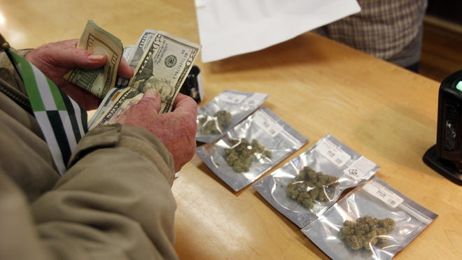 In this Monday, Jan. 1, 2018 file photo, a customer purchases marijuana at the Harborside marijuana dispensary in Oakland, Calif., on the first day that recreational marijuana was sold legally in California. State regulators get credit for taking on the massive job of transforming the longstanding illegal and medicinal marijuana markets into a unified, multibillion-dollar industry, but the results have been mixed. Some companies are doing well, but many others are not.