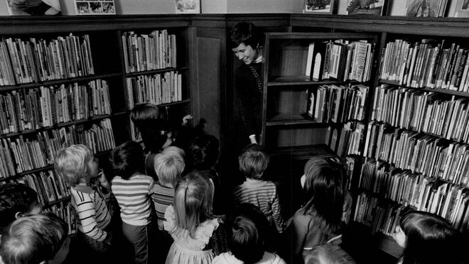 Librarian Barbara Billingsley shows a group of children how to open the door to the “Secret Room” at the Rundel Library in 1986.