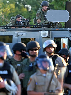 A police sharp shooter keeps an eye on protesters along W. Florissant Avenue on Tuesday, Aug. 12, 2014 near the QuikTrip that was burned down a few days earlier in Ferguson. (AP Photo/St. Louis Post-Dispatch, David Carson)