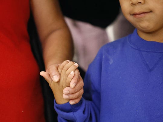 A mother and son from Guatemala hold hands during a