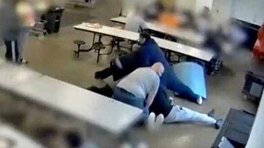 A frame capture from surveillance video footage from the Lakeside Academy in Kalamazoo shows 16-year-old Cornelius Fredericks being pushed to the floor and held down by staff members because he threw a sandwich in the cafeteria.