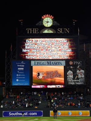 A scoreboard message asks fans to remain in the ballpark due to Freddie Gray protests during the middle of the ninth inning.