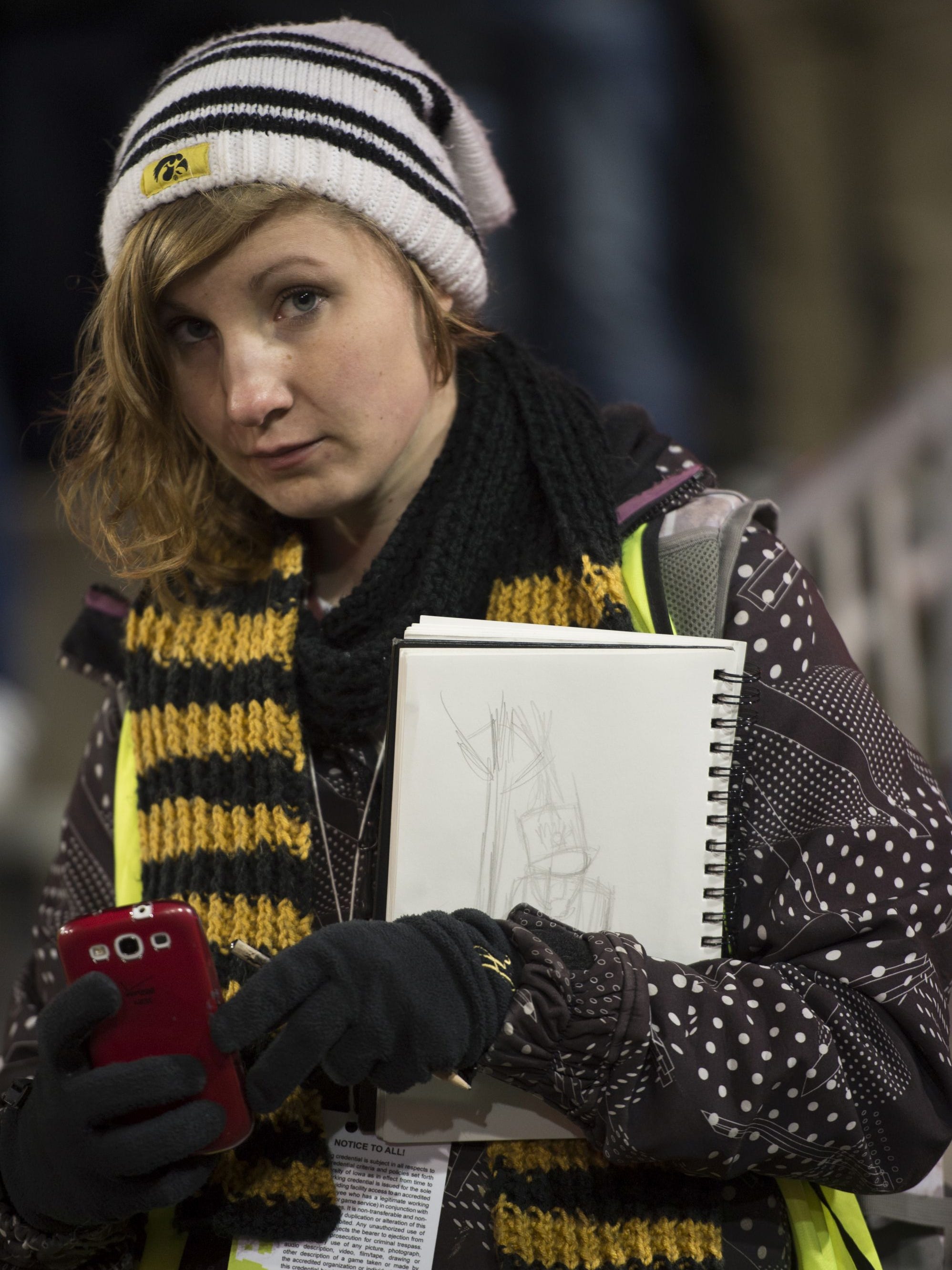 Heidi Schickel, a recent graduate in the UI School of Art and Art History, sketches from the sidelines of Kinnick Stadium during Iowa football games.