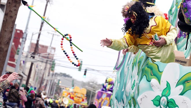 A rider tosses beads and a spear to revelers as the 2015 Lafayette Mardi Gras King Gabriel Parade rolls through Lafayette.