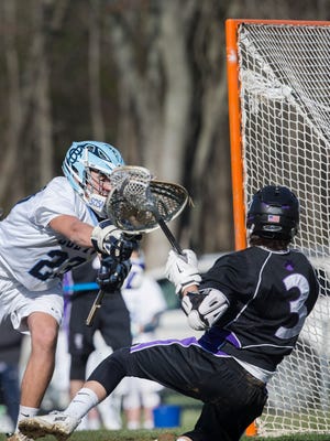 Rumson’s Griffin Schultz gets knocks down as he takes a shot on goal by CBA’S Ryan McGuinness causing the short to go wide. Rumson-Fair Haven Boys Lacrosse vs Christian Brother Academy in Middletown, NJ on April 12, 2016