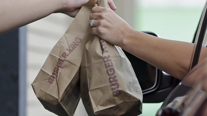 In this Monday, Oct. 31, 2016, photo, a customer picks up an order at a Burger King drive-thru in Miami. Burger King is adding spicy nuggets to its menu and firing up a rivalry with burger chain Wendyâs, which pulled the peppery snack from most of its restaurants earlier in 2017. (AP Photo/Alan Diaz)