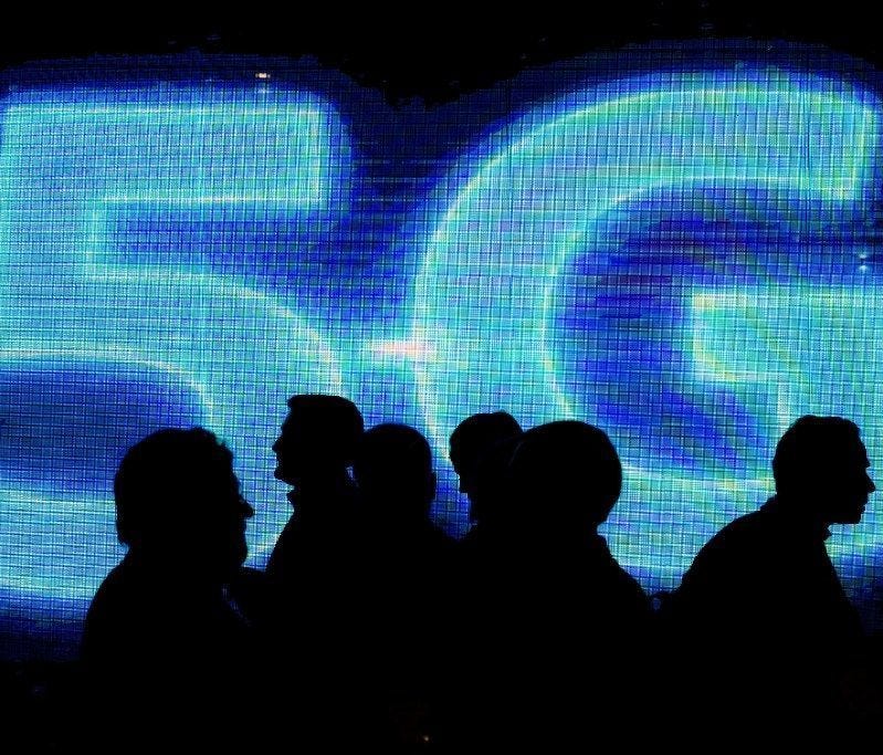 Visitors walk past a 5G logo during the Mobile World Congress on the third day of the MWC in Barcelona, on March 1, 2017.