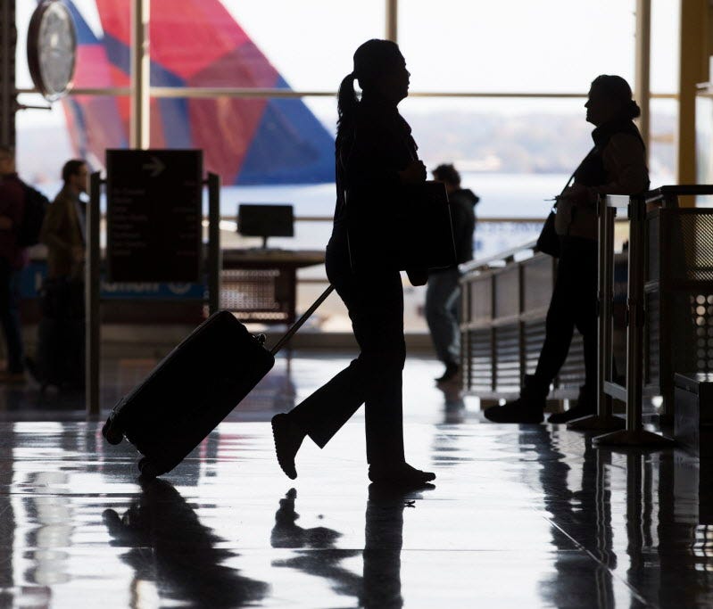 A traveler pulls a luggage in front of an aircraft seen at Ronald Reagan Washington National Airport in Arlington, Va., on Nov. 22, 2017.