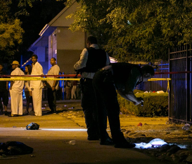 In this Aug. 7, 2016, photo, Chicago police investigate a scene in Chicago where gunfire at a birthday party left a man dead and a woman injured. Police on Monday said they were searching for suspects involved fatal shooting of a 15-year-old boy who 