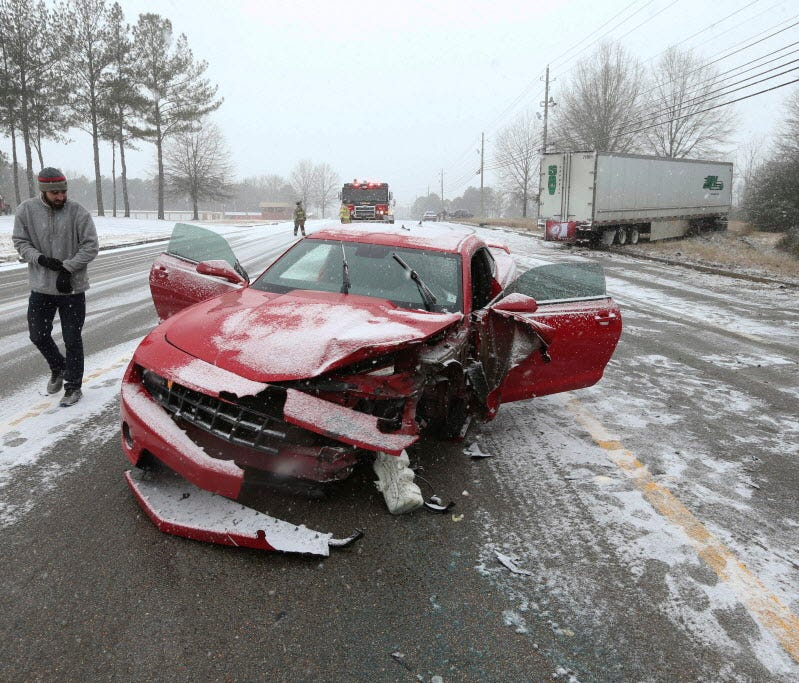 Brandon Reddout looks at the damage done to his car after he was struck by a tractor trailer which ran off the road shortly after the collision on West Main Street in Tupelo, Miss., on Jan. 16, 2018.