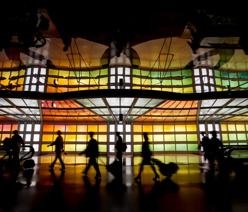 Travellers traverse Chicago O'Hare's unique rainbow light tunnel, connecting terminals B and C, on April 24, 2016.