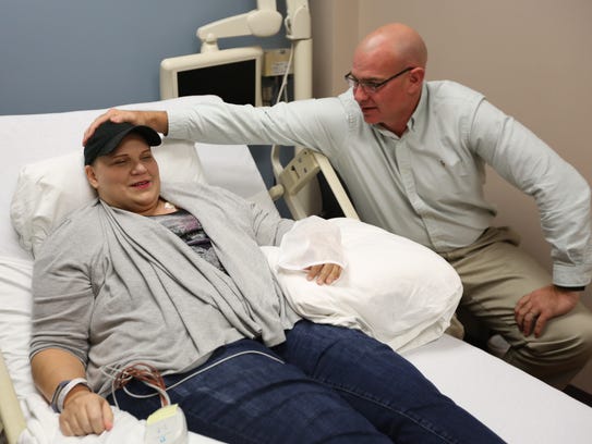 Jason Newton, 47, of Handy Township touches his wife, Kimberlie Newton, in the only place that doesn't hurt after she receives a new hormonal agent in the phase 1 clinical trial to treat breast cancer at the Karmanos Cancer Institute in Detroit on Wednesday, Oct. 25, 2017. Newton has 4 estrogen receptor-positive (ER positive) breast