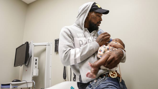 DeMario Stewart, 27, of Flint said feeds his son Damonei Stewart during his two month check-up at Hurley Children's Center at the Flint Farmers' Market in Flint on Thursday, Oct. 22, 2015.