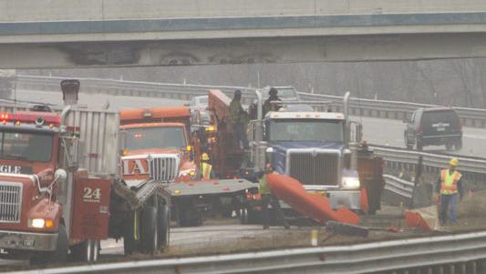 Workers remove debris from the truck that hit the Eight Mile overpass to U.S. 23 in Green Oak Township Thursday morning.