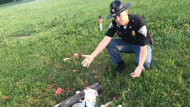 Indiana State Polcie Sgt. John Perrine crouches near an obliterated box of powdered doughnuts. Wayne Township Fire Department Capt. Mike Pruitt blew up the box to remind people to use fireworks responsibly on July Fourth.