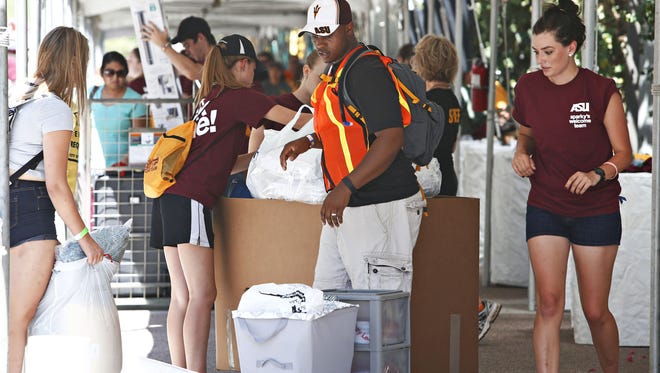 Ronald Briggs, in vest, the Assistant Dean of Students at the Downtown Phoenix Campus, helps students move into Taylor dorm downtown as seen in Phoenix on August 14, 2015