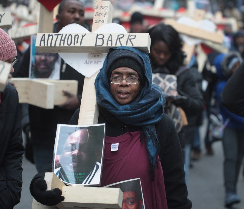 Melva Pratt carries a cross as she marches with other residents, activists, and family members of victims of gun violence down Michigan Avenue on December 31, 2016 in Chicago, Illinois. Nearly 800 people have been murdered in the city this year and m