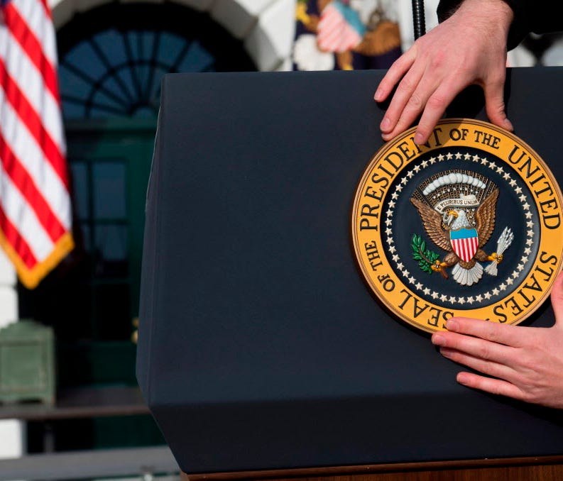 A staff member places the presidential seal on the podium prior to President Trump speaking at the White House on Dec. 20, 2017.