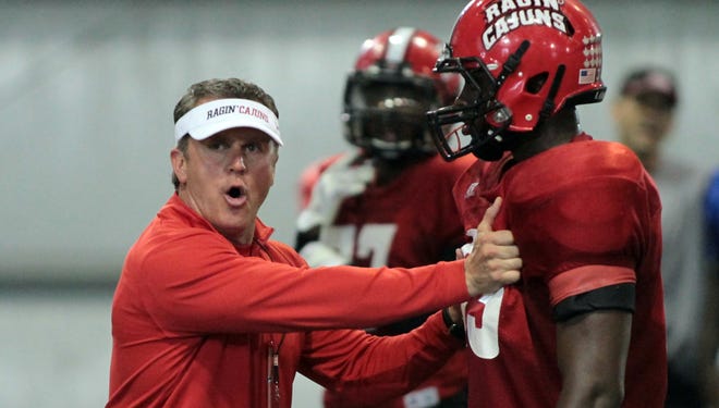 UL Head Football Coach Mark Hudspeth runs through a drill with players during practice at the Leon Moncla Indoor Practice Facility in Lafayette.