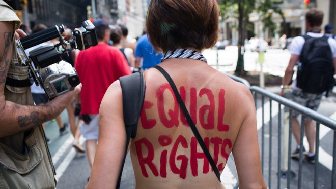 An activist marches in the protest march called the GoTopless Day Parade Sunday, Aug. 23, 2015, in New York. The parade took to the streets to counter critics who were complaining about topless tip-seekers in Times Square. Appearing bare-breasted is legal in New York. But Mayor Bill de Blasio and police Commissioner Bill Bratton say the body-painted women in the square who take photos with tourists are a nuisance.