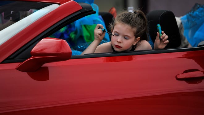 MacKenzie Lambert, 9, uses the rearview mirror on the convertible she is riding in to put on mascara Thursday, March 8, 2018. She was riding in the car with other members of the Sweetwater Performing Arts Center in the parade for World's Largest Rattlesnake Roundup. Friday will mark the 60th anniversary of the event.