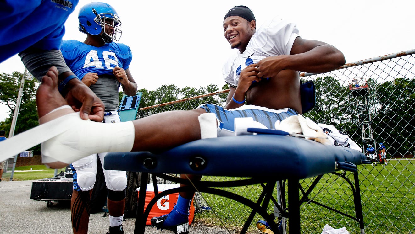 Football player getting his ankles taped with athletic tape