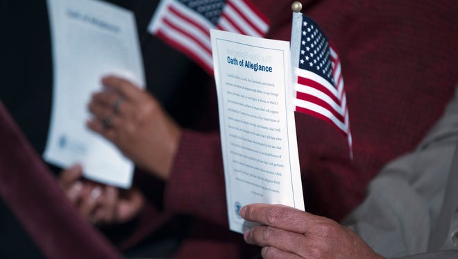 In this Dec. 15, 2015 photo, participants hold the "Oath of Allegiance" and American flags during a naturalization ceremony attended by President Barack Obama at the National Archives in Washington. Asians remain the fastest-growing racial group in the United States, according to new information from the Census Bureau. The nation's Asian population grew at 3.4 percent between July 2014 and 2015, with migration responsible for the majority of the growth, government officials said Thursday, June 23, 2016.