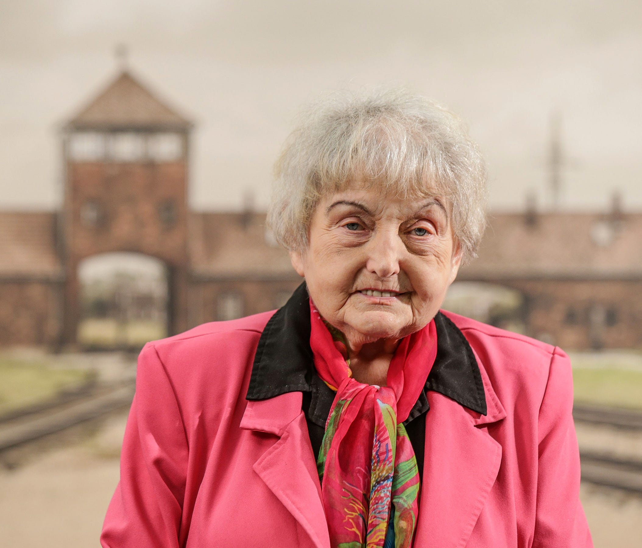 Holocaust survivor Eva Mozes Kor stands April 6, 2017, in front of a contemporary photo of the selection platform at the Auschwitz-Birkenau camp on display at the CANDLES Holocaust Museum and Education Center in Terre Haute, Ind.