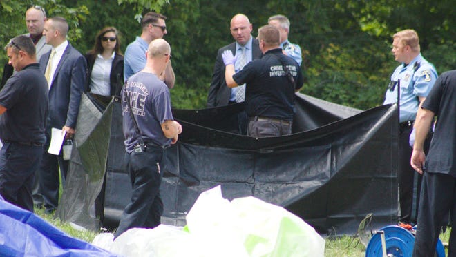Police and fire crews work to pull a body out of a sewer line in Lansing. The body was discovered by a public service employee at about 10 a.m. Tuesday, Aug. 21, 2018.