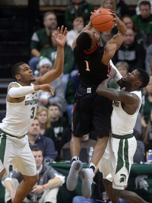 Eron Harris, right, and Alvin Ellis III go up to block Northeastern's Shawn Occeus during Michigan State's 81-73 loss Sunday in East Lansing.