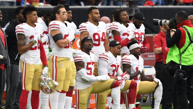 San Francisco 49ers outside linebacker Eli Harold (57), strong safety Eric Reid (35), and wide receiver Marquise Goodwin (11) kneel for the national anthem prior to the game against the Houston Texans at NRG Stadium.